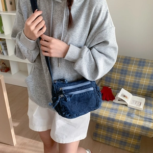Detail of dark blue denim crossbody bag with multiple zippers and adjustable shoulder strap