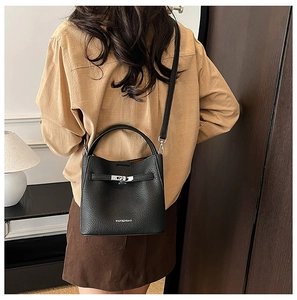 Detail of black lychee grain leather bucket bag with silver twist lock and brand logo