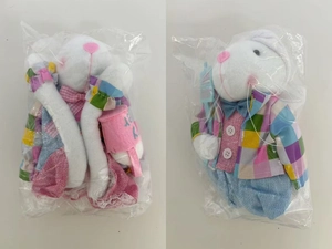 Group of white Easter plush bunnies in colorful plaid clothes inside clear plastic packaging