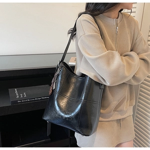 Macro detail of black bucket bag featuring textured faux leather and embossed logo design