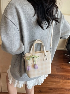 Sac seau à carreaux beige avec breloque tulipe et nœud porté par un mannequin
