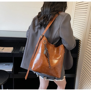 Detailed view of a vintage brown bucket bag worn with a gray suit for a chic daily look