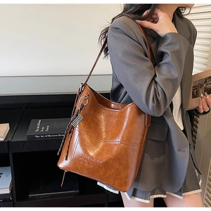 Detail of brown bucket bag with cross-stitch pattern and debossed MKXO logo text