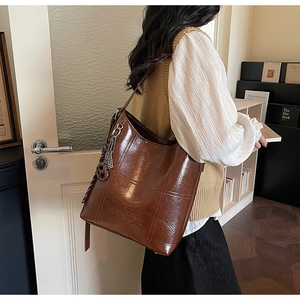 Close-up of deep brown bucket bag featuring cross-stitching and embossed MIXXO logo detail