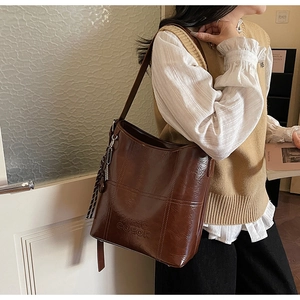 Macro shot of brown oil wax leather bucket bag with logo embossing and silk scarf detail