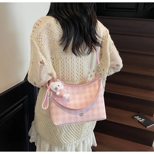Sac seau rose à carreaux avec charm en peluche porté par femme en pull beige