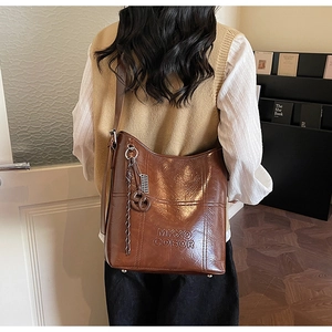 Detailed macro view of vintage brown leather bucket bag with debossed logo and ring charm