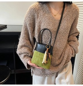 Mini green suede bucket bag featuring black leather trim and beaded tassel details