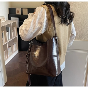 Detail of dark brown glossy leather bucket bag with vintage texture and stitched logo