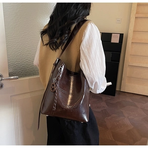 Close-up of deep brown glossy leather bucket bag with embossed logo and metal ring detail