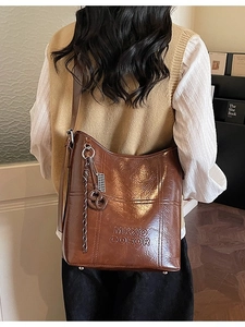 Classic dark brown leather bucket bag in large capacity shown on model's shoulder