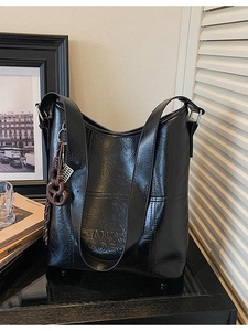 Retro black bucket bag in glossy faux leather with embossed letters and charms