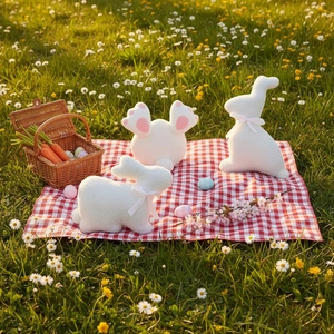 Easter bunny plush pillows with bow ties and fluffy tail on grass with picnic basket