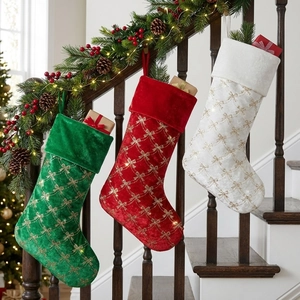 Three-piece set of velvet Christmas stockings with golden bows hung on a staircase