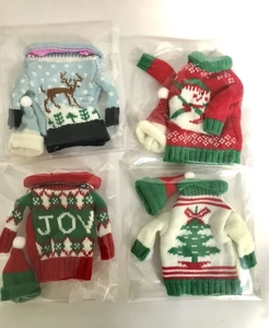 Detail of four knit Christmas wine bottle sweaters and hats with elk and snowman patterns