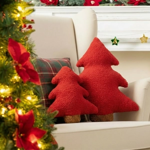 Red teddy fleece Christmas tree pillows set on an armchair in a festive home setting