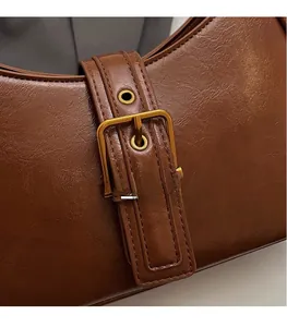 Detail of vintage brown leather handbag featuring textured PU and antique gold metal buckle