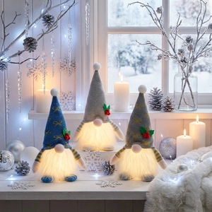 Dettaglio di tre gnomi natalizi luminosi con cappelli in maglia su un davanzale invernale