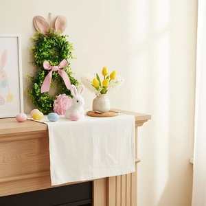 Close-up of Easter rabbit ear wreath with colorful eggs on a rustic linen table runner