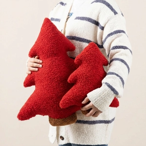 Detail of soft red teddy velvet Christmas tree pillows held to show plush texture
