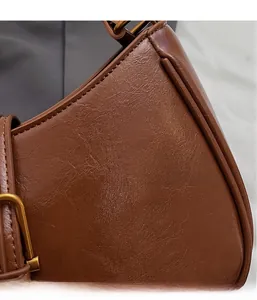 Detail of brown oil wax leather bag with pleated texture and vintage gold metal hardware