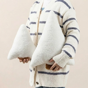 Close-up of plush white Christmas tree-shaped pillows held by a model for festive home decor