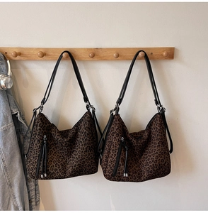 Close-up of leopard print hobo bag hanging with slim shoulder straps and zip details