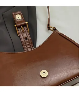 Detail of vintage brown faux leather shoulder bag with magnetic snap and metal buckle