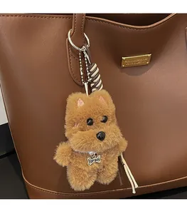 Detail of plush dog bag charm with pearl necklace and TOP DOG bone tag on leather tote
