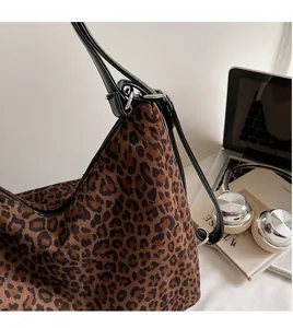Close-up of leopard print shoulder bag with smooth long strap on a white desk
