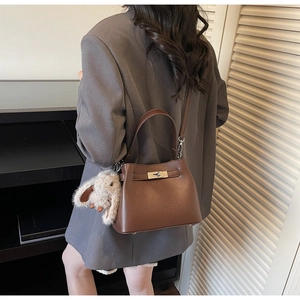 Detail of brown lychee leather handbag with metal turn-lock and cute rabbit pendant