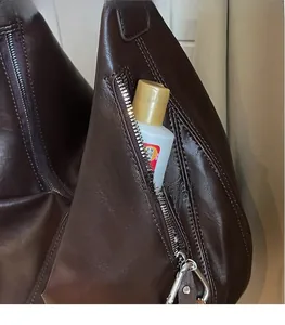 Detail view of dark brown faux leather tote bag showing the side zipper storage pocket