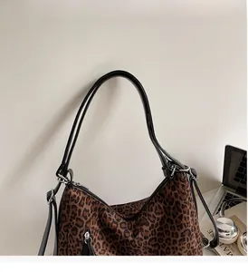 Detail of the leopard print tote bag with durable leather straps and metal hardware