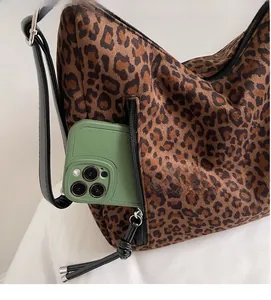 Detail of leopard print tote side pocket showing storage capacity with a smartphone