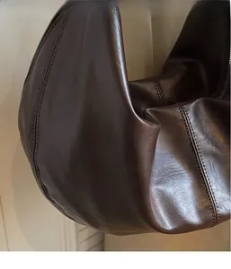 Detail shot of the fine texture and stitching on the dark brown crescent bag's faux leather