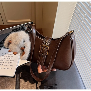 Detail of dark brown vintage shoulder bag with retro metal buckle and plush bunny charm