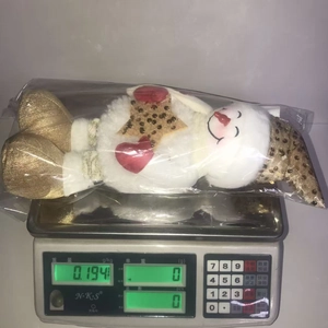 Detail view of a sequined Christmas snowman doll showing its weight on an electronic scale