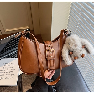 Close-up of vintage brown crescent bag with metal buckle and plush rabbit charm