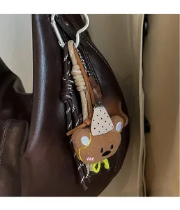 Detail of cute plush bear charm with polka dot hat on brown leather tote bag