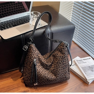 Detailed view of leopard print tote bag featuring dual zippers and black leather straps