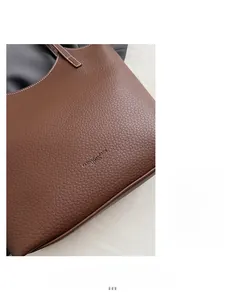 Detail of dark brown lychee grain leather tote bag with embossed text and soft texture