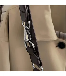 Close-up of polished silver metal hooks and sturdy shoulder strap on a brown tote bag