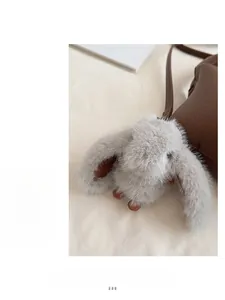 Détail d'un charme lapin en peluche avec touches de cuir sur un sac seau marron