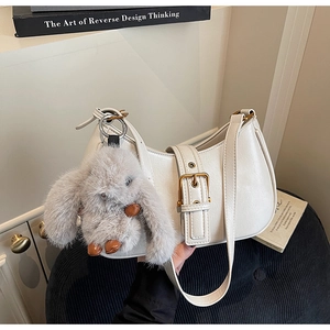 Close-up of white hobo bag with gold buckle detail and a cute grey bunny plush charm