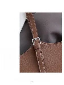 Detail of brown lychee grain leather bag with adjustable silver metal buckle and stitching