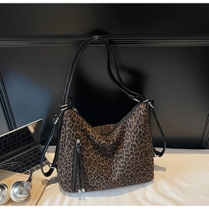 Detail view of leopard print tote bag with vertical zippers and elegant black shoulder straps