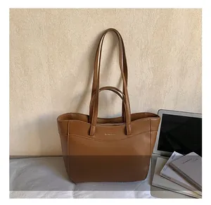 Detailed view of caramel brown leather tote bag with curved stitching and dual straps