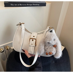 Detailed close-up of a white crescent hobo bag with gold buckle and plush rabbit charm