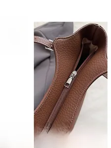 Detail of silver zipper closure and grain leather texture on brown tote bag