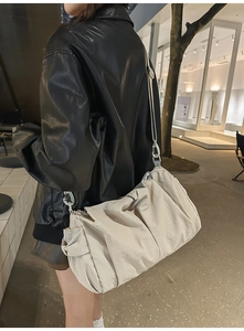 Detail of a large off-white pleated tote bag with nylon texture and metal buckle accents